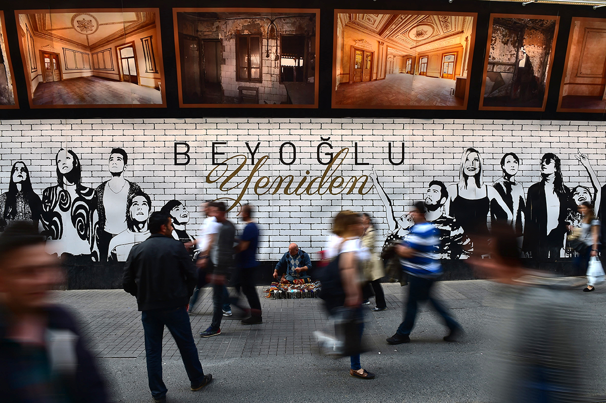 #100 —Beyoğlu - 
Bedensel engelli seyyar satıcı kalabalığa aldırmadan yere kurduğu tezgahını düzenliyor.