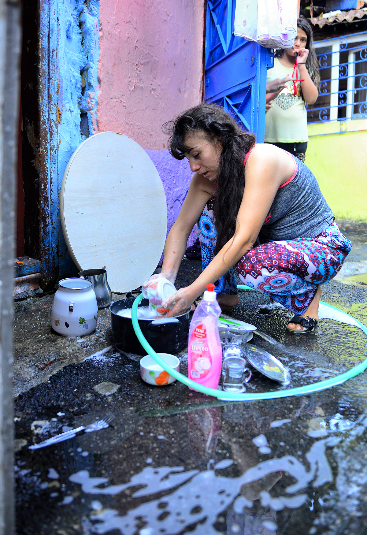 #242 —Sarıyer - 
A woman washing dishes on the street.